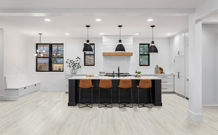 wood look laminate flooring in kitchen with dark kitchen island and leather stools